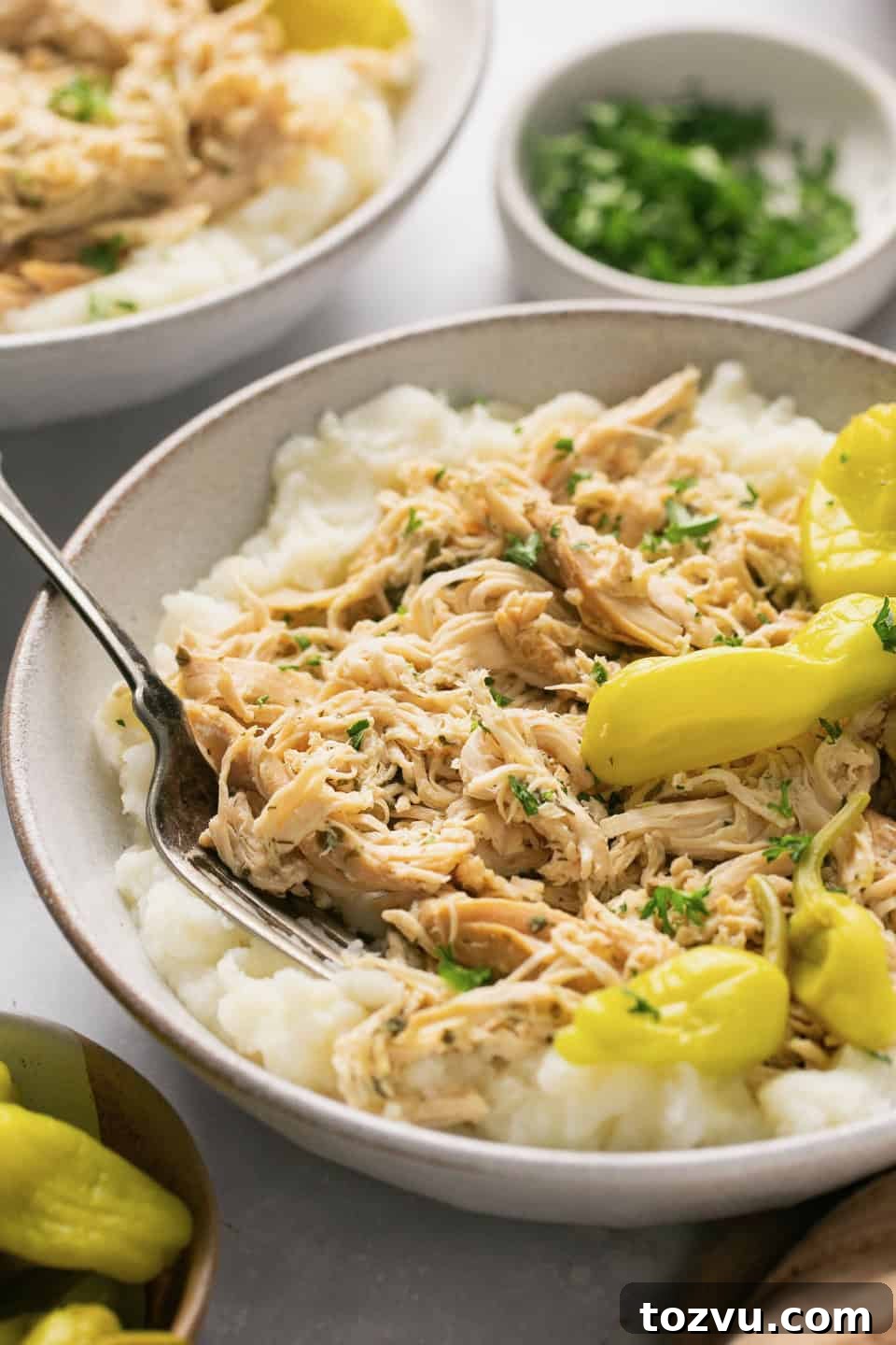 Mississippi Chicken: 3 Flavorful Variations 2 a white bowl filled with mashed potatoes, shredded chicken, and pepperoncini peppers