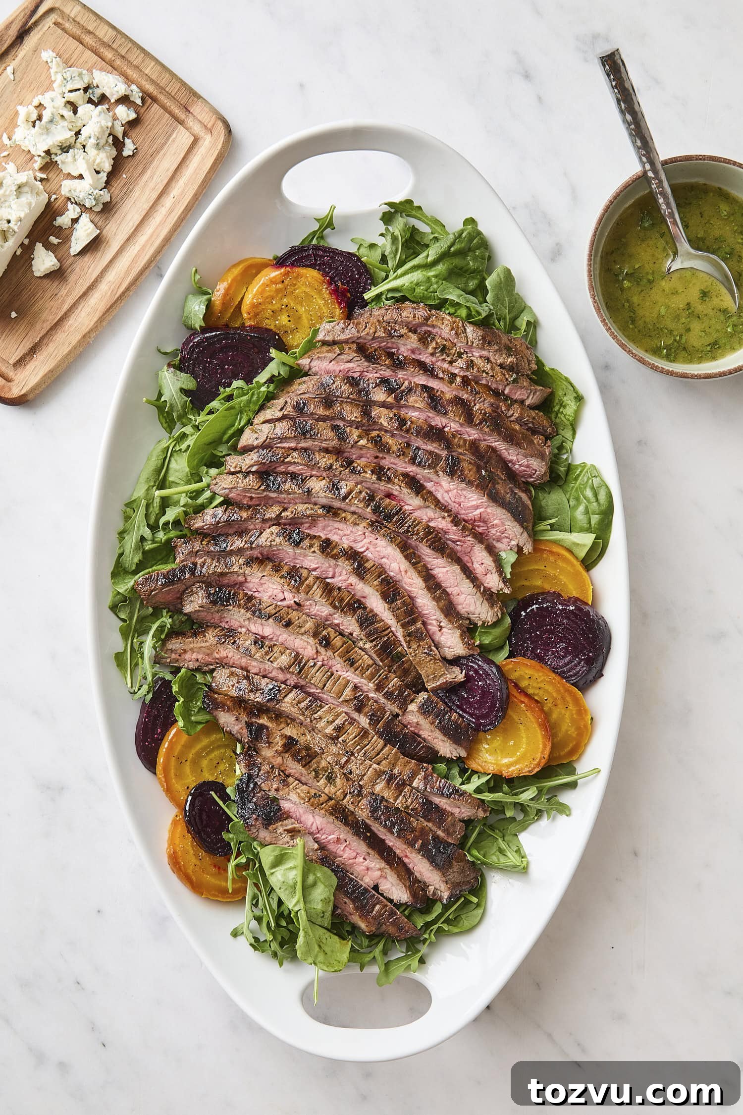 Grilled Steak with Roasted Beet and Goat Cheese Salad 12 White platter with assembly of steak and beet salad on spinach and arugula.