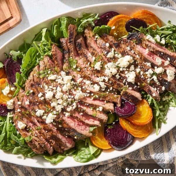 Grilled Steak with Roasted Beet and Goat Cheese Salad 14 White platter with steak and beet salad with crumbled blue cheese and dressing on top.