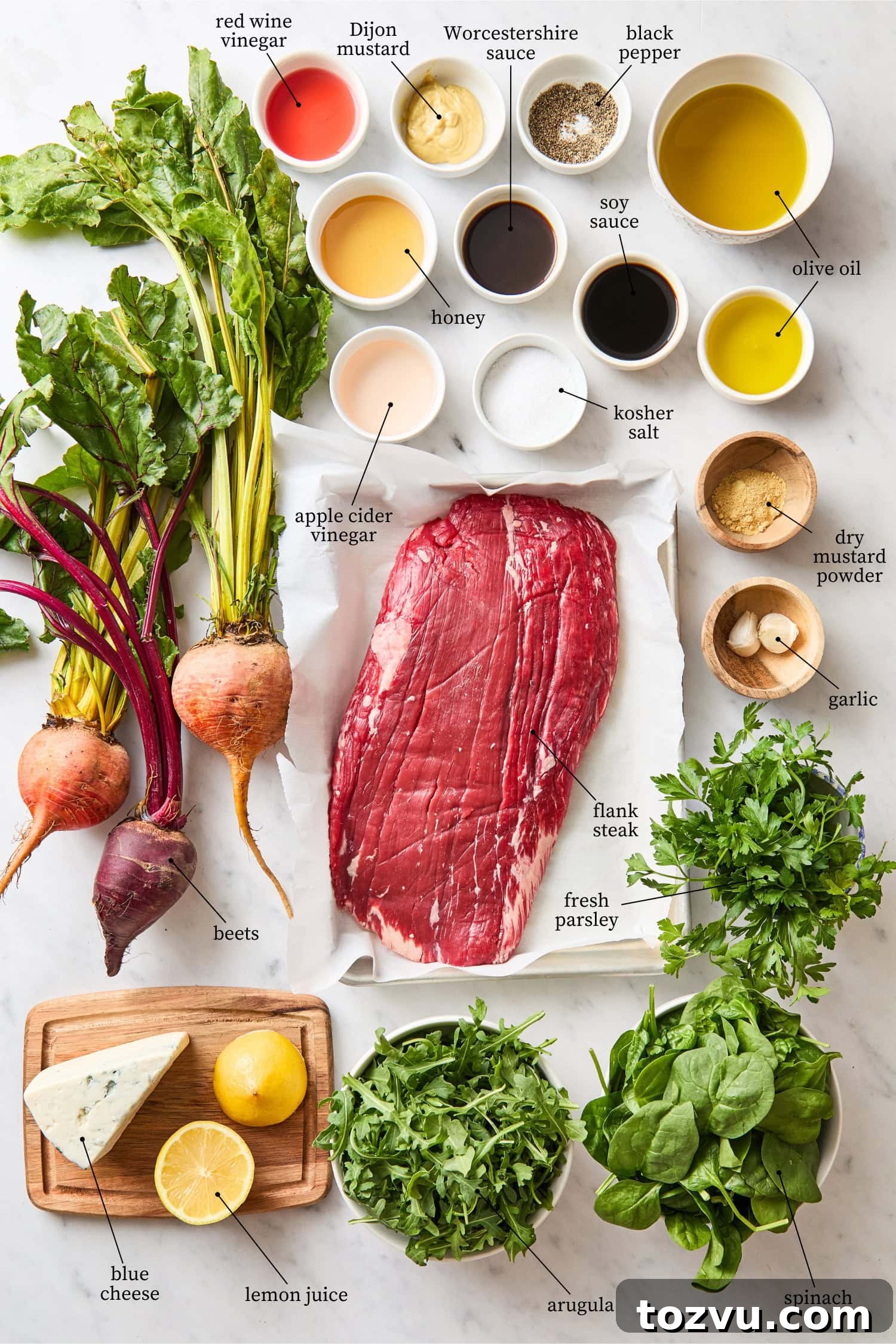Grilled Steak with Roasted Beet and Goat Cheese Salad 4 White marble surface with ingredients needed for steak and beet salad including flank steak, beets, herbs, arugula, and more.