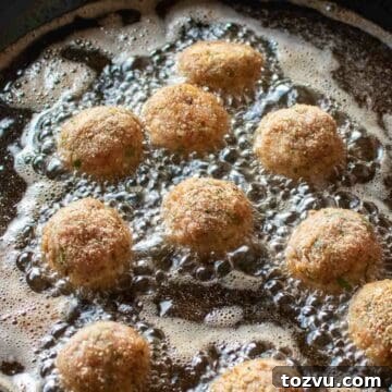 Crispy Fried Meatballs with Garlic Dipping Sauce 7 Meatballs frying in oil.