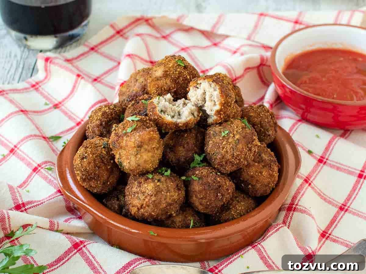 Crispy Fried Meatballs with Garlic Dipping Sauce 9 Meatball broken in half sitting on top of a pile of browned meatballs.