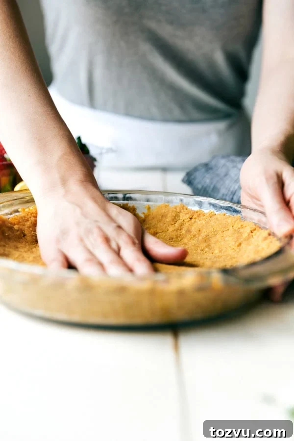 Pressing pie crust A hand pressing down the pie crust in the clear pie pan.