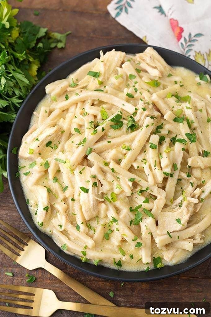 Creamy Instant Pot Chicken and Noodles Recipe 2 Instant Pot Chicken and Noodles in a black bowl on wooden board next to golden forks