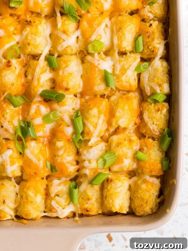 Buffalo chicken tater tot casserole in a baking dish and topped with shredded cheese and green onions.