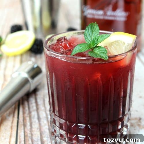 Blackberry Smash Cocktail made with blackberries, whiskey, and mint in a cut crystal low ball glass.