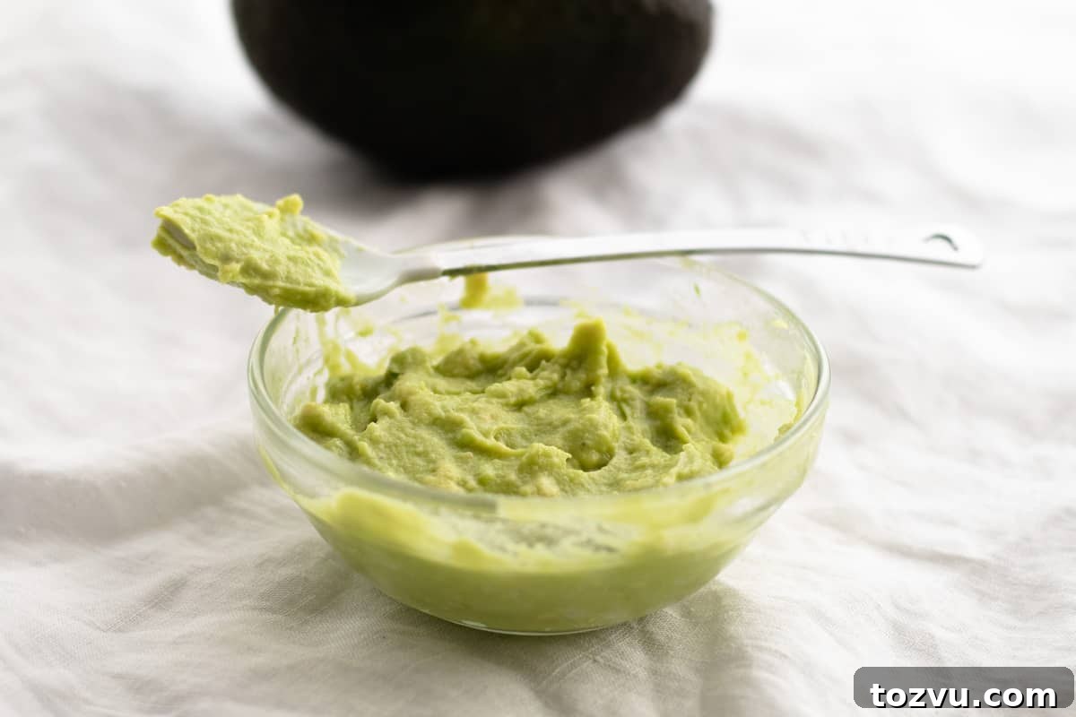 How to Make Avocado Puree for Baby Food 8 glass dish with puree and avocado behind it