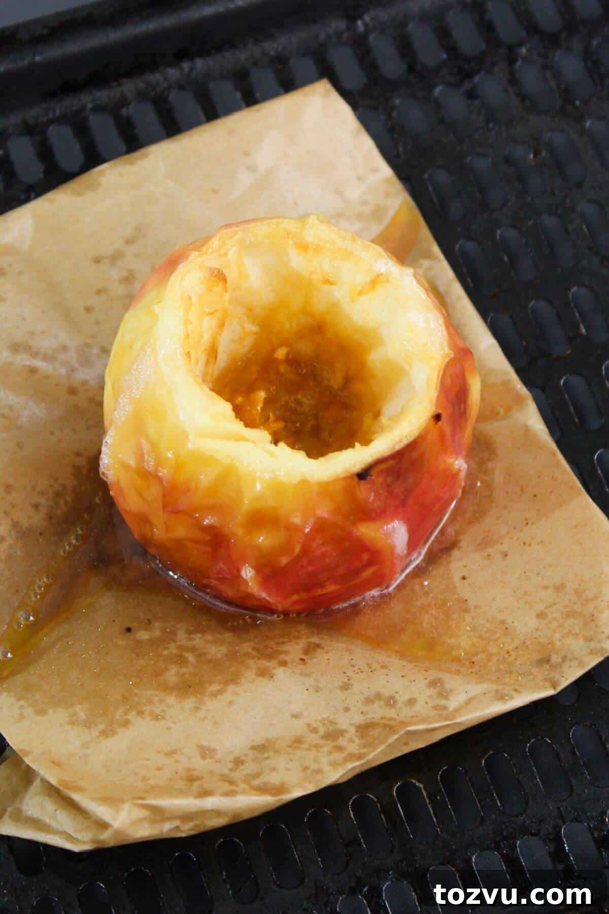 Air Fryer Baked Apples with Cinnamon and Brown Sugar 8 A hollowed-out apple rests on parchment paper atop a baking tray, ready to transform into a delicious baked apple in the air fryer.