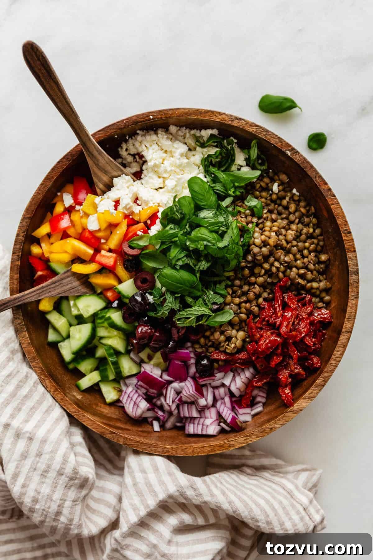 Zesty Mediterranean Lentil Salad with Feta and Fresh Herbs 2 Mediterranean lentil salad in a wood bowl with wood spoons and a napkin on the side.