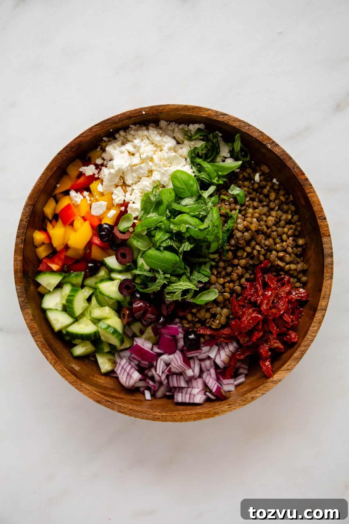 Zesty Mediterranean Lentil Salad with Feta and Fresh Herbs 4 lentils, vegetables, herbs and feta cheese in a wood bowl.