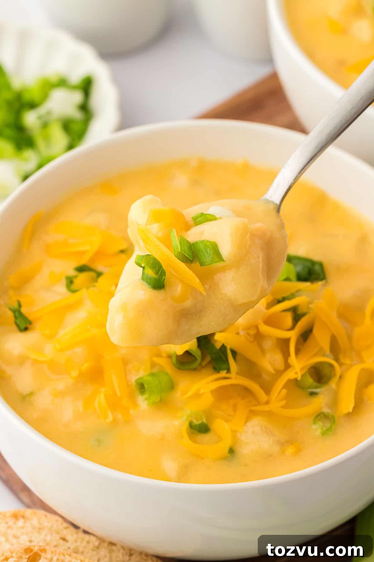 potato soup in a bowl topped with green onions and cheddar cheese