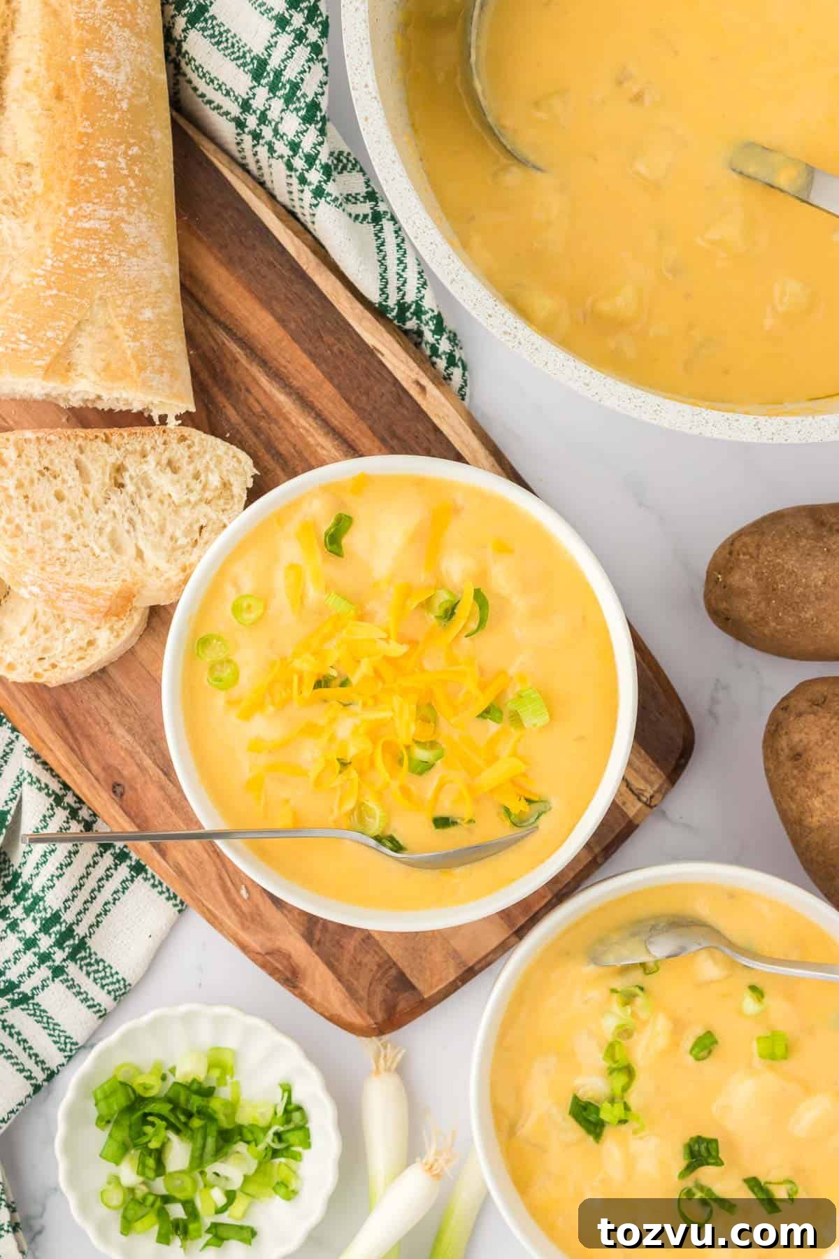 potato soup in a bowl topped with green onions and cheddar cheese