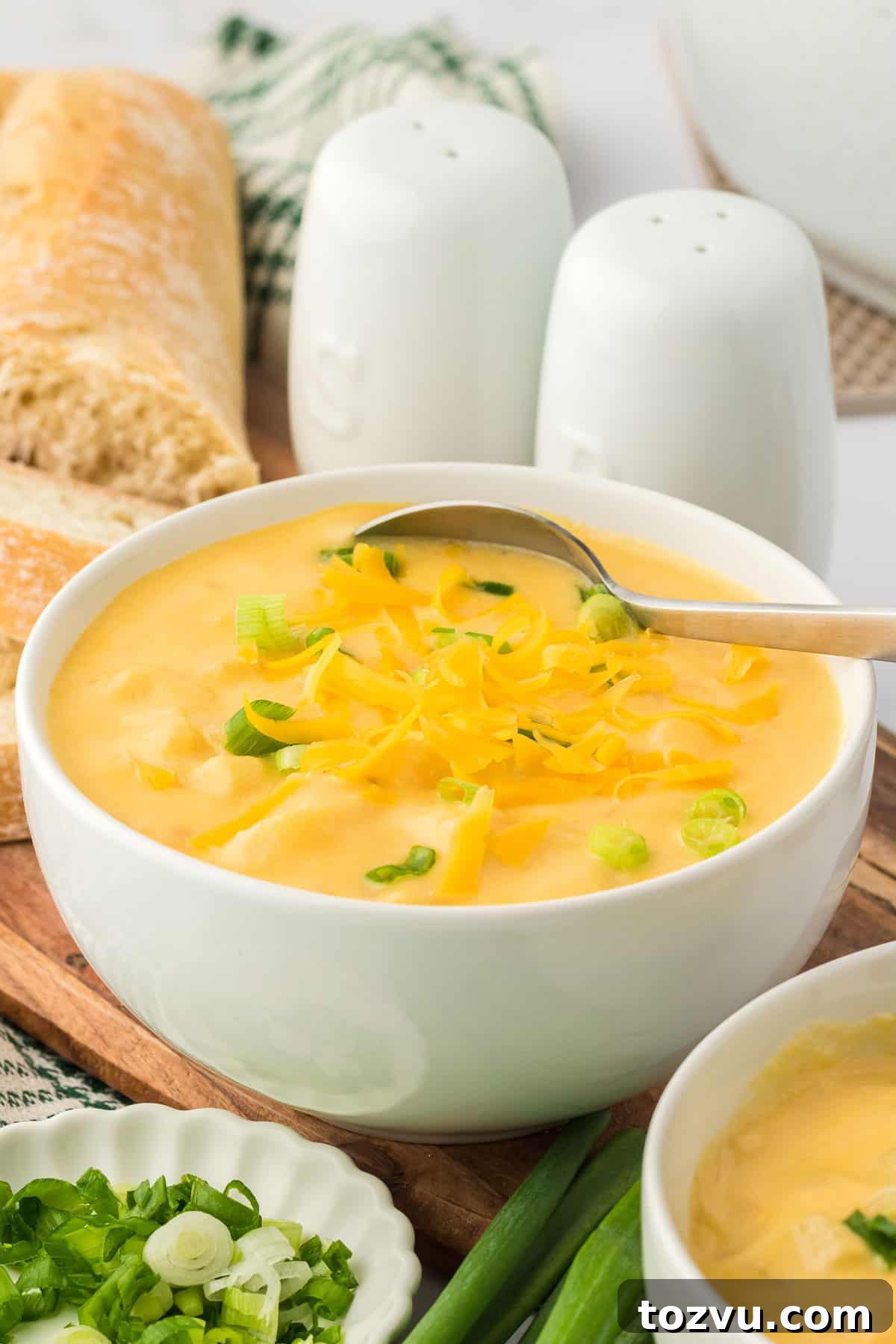 potato soup in a bowl topped with green onions and cheddar cheese