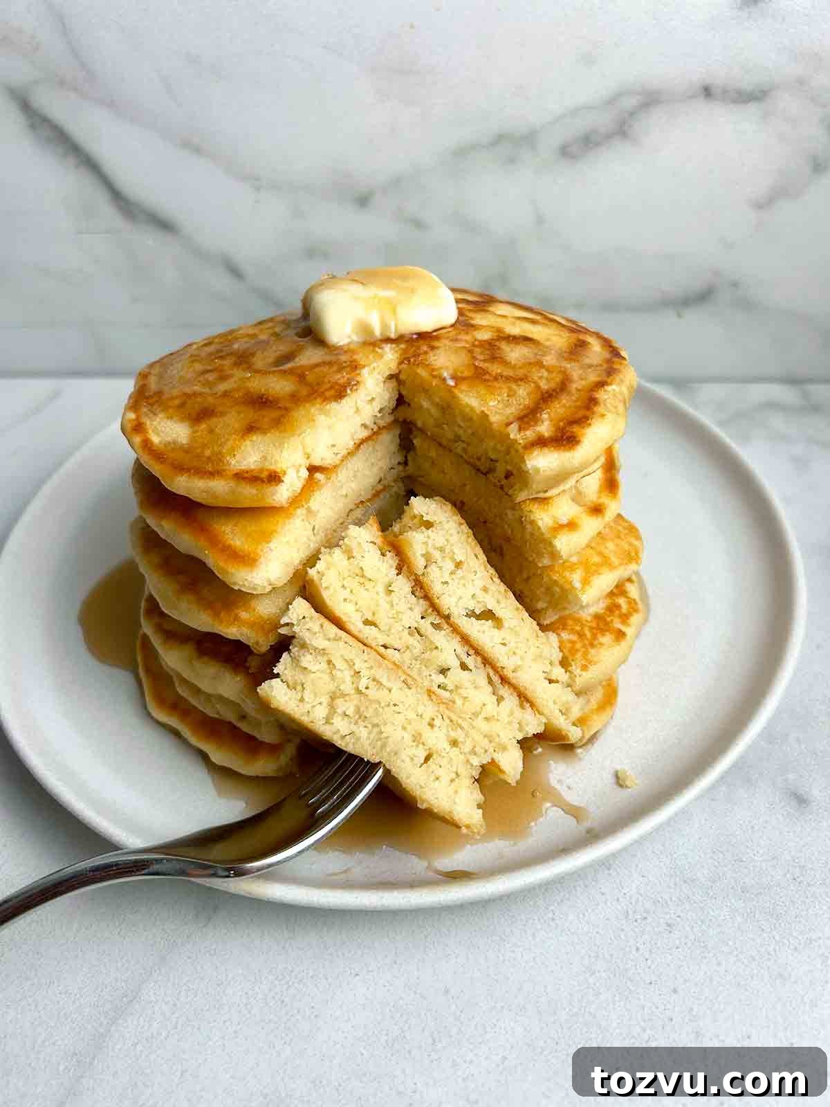 Fluffy Dairy-Free Pancakes Without Milk 2 stack of pancakes with section cut through all of them to show the fluffy inside.