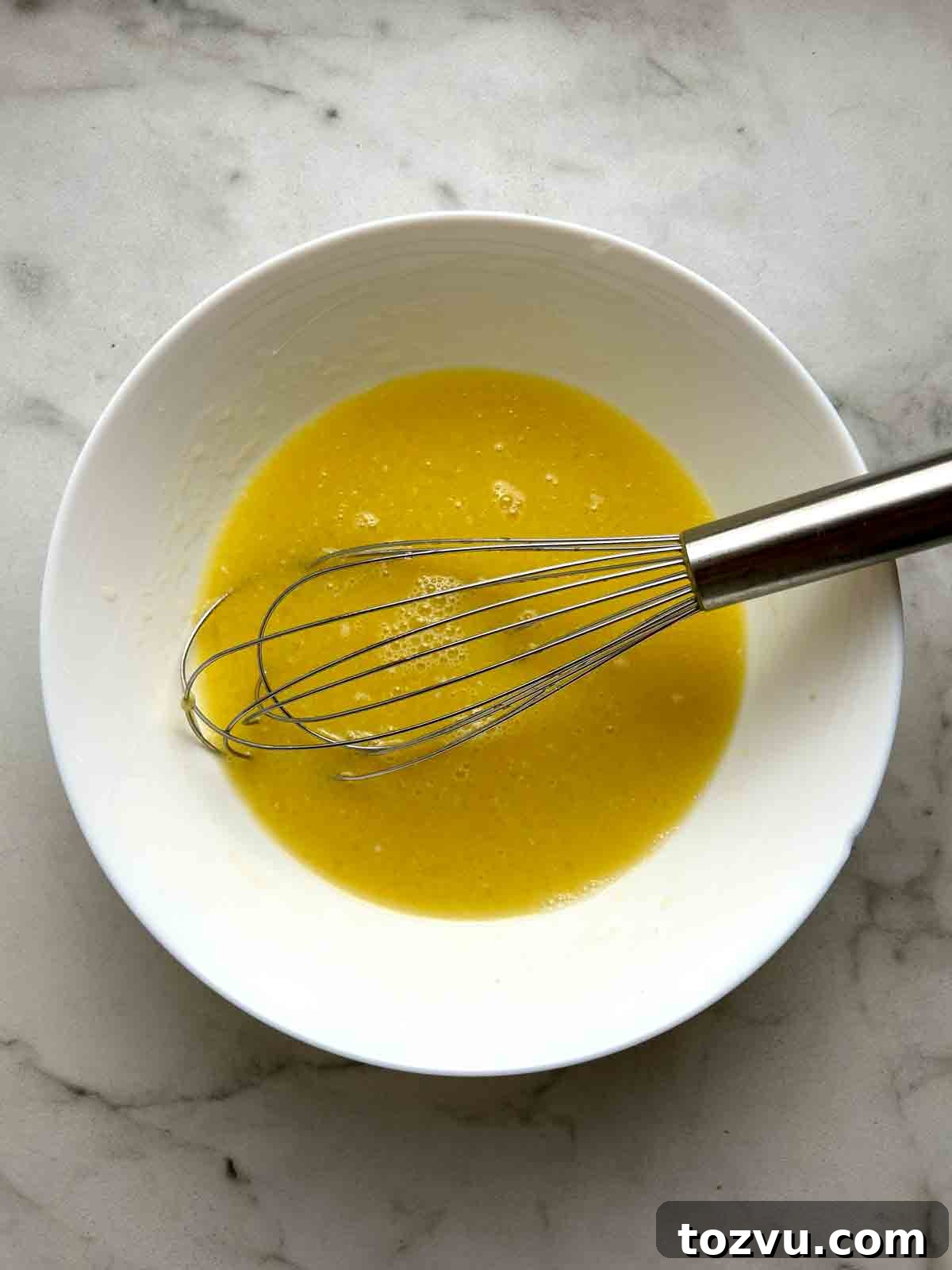 Fluffy Dairy-Free Pancakes Without Milk 5 wet mixture whisked in white bowl.