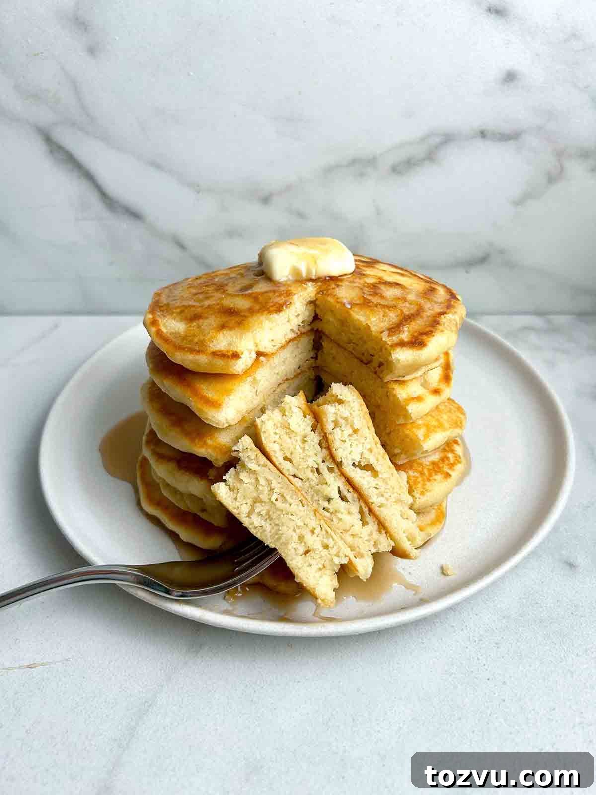 Fluffy Dairy-Free Pancakes Without Milk 9 stack of pancakes with section cut through all of them to show the fluffy inside.