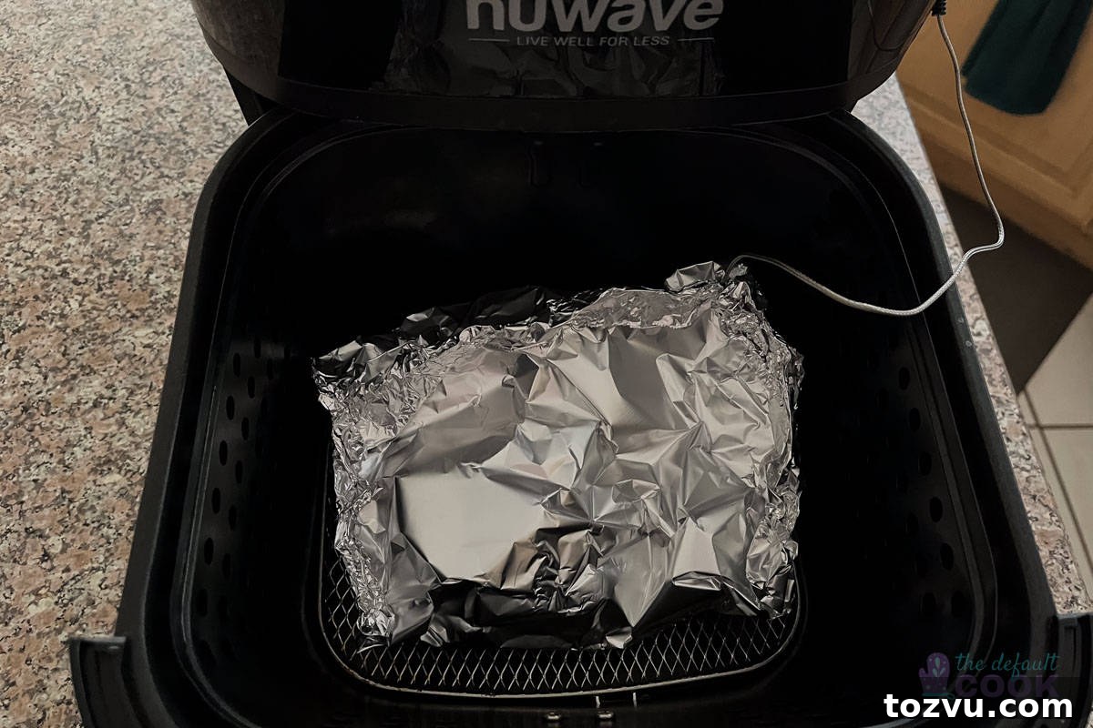 Trader Joe's Salmon Pinwheels Recipe with Feta and Spinach 5 An air fryer basket with a foil packet containing food, with a temperature probe inserted into the side of the packet.