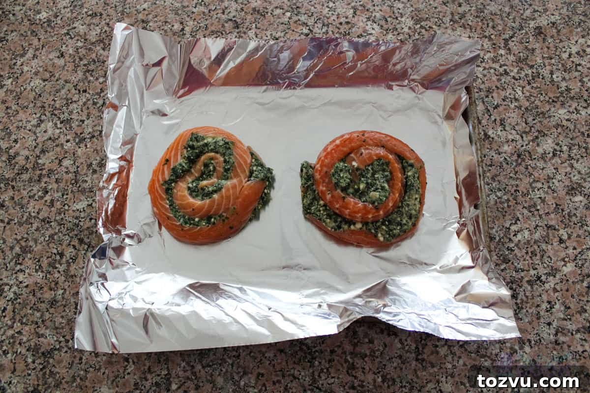 Trader Joe's Salmon Pinwheels Recipe with Feta and Spinach 6 Two raw salmon pinwheels stuffed with spinach and cheese placed on an aluminum foil lined baking sheet.
