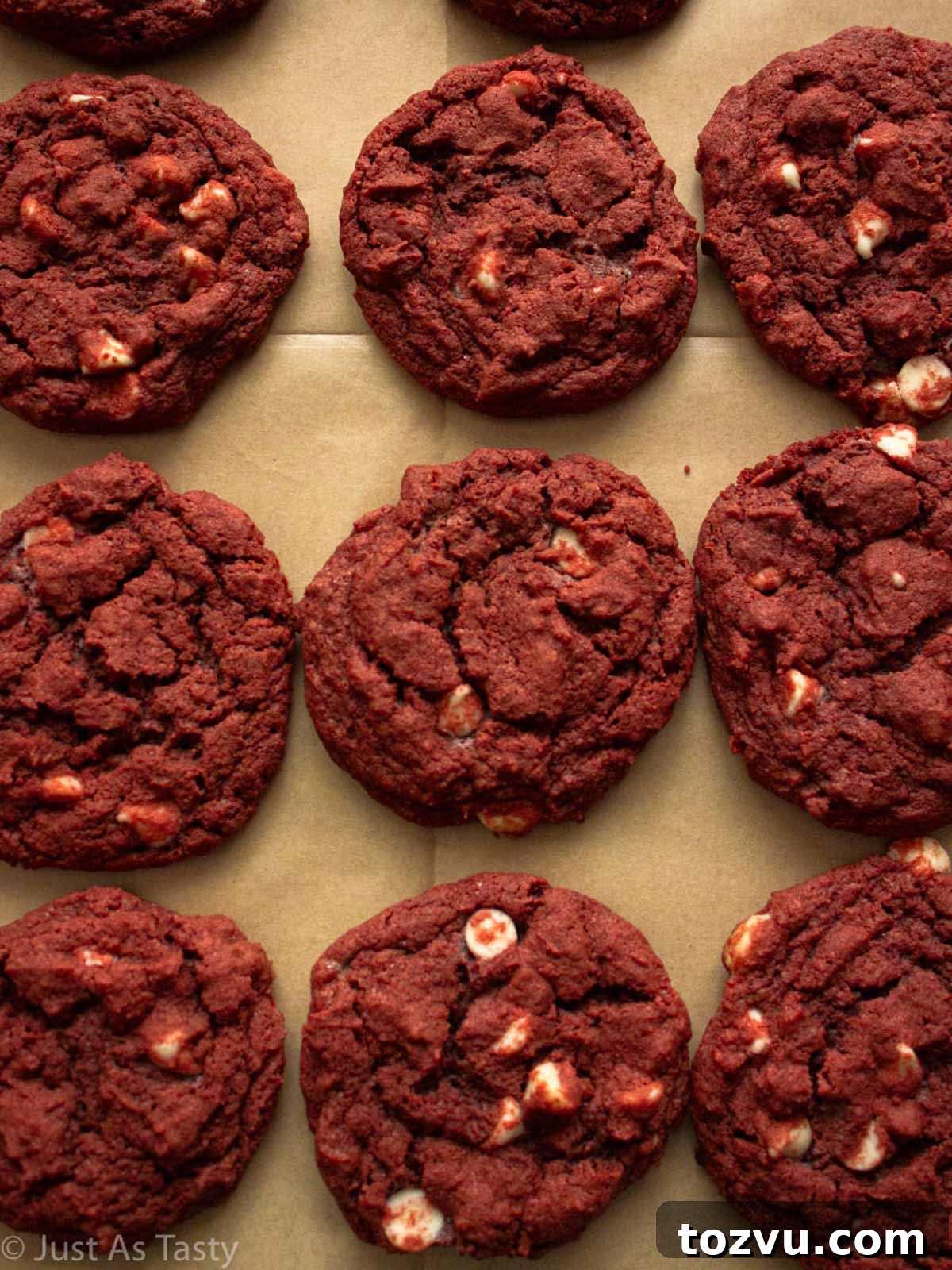 Red velvet chocolate chip cookies lined up on parchment paper.