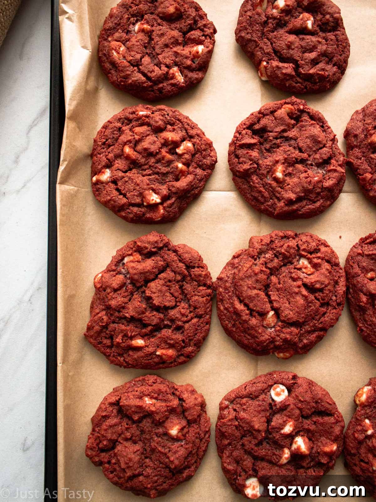Red velvet chocolate chip cookies on a lined baking sheet.