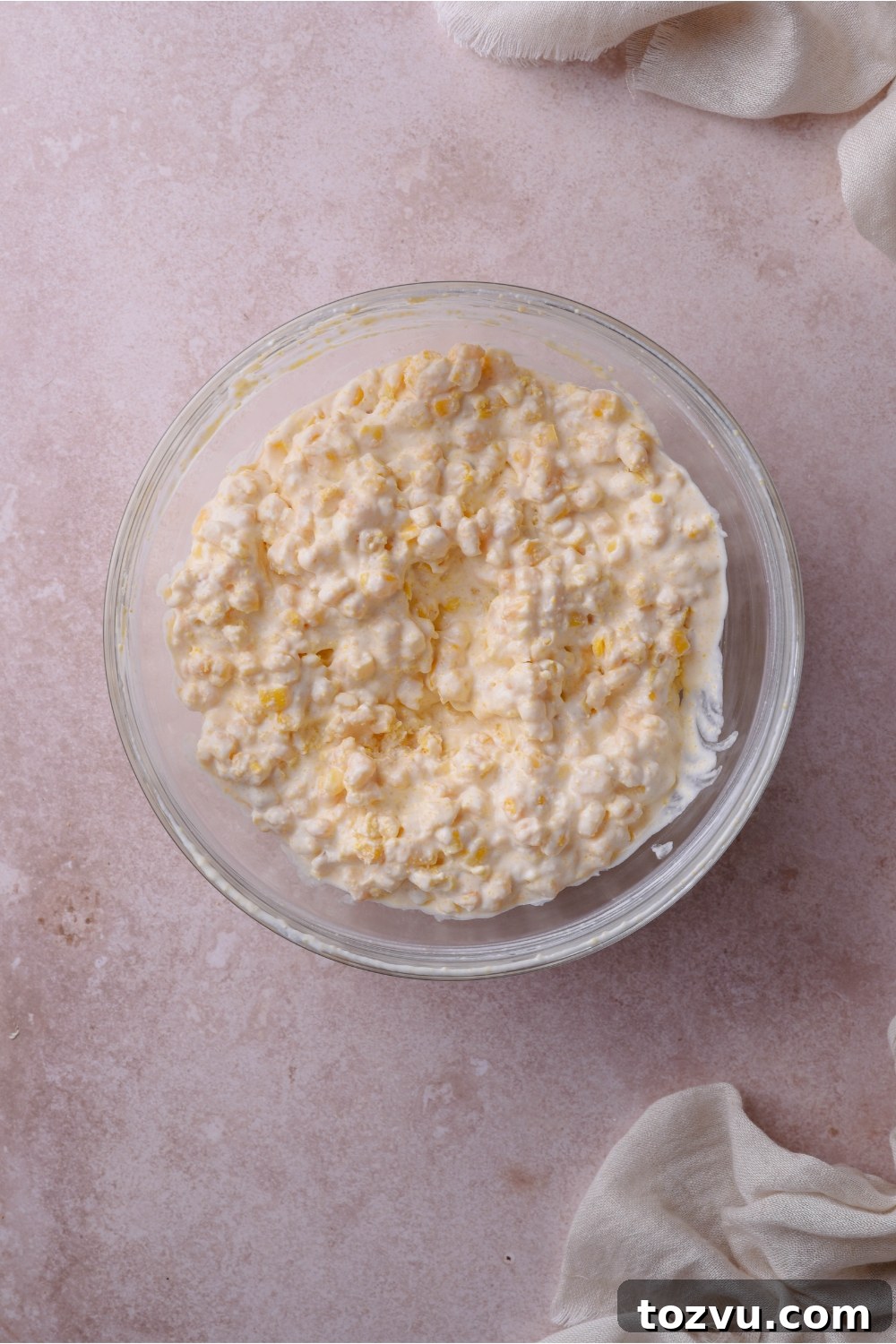 A clear bowl filled with a creamed corn mixture.