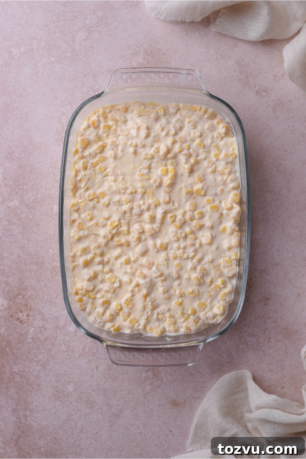 A baking dish filled with unbaked creamed corn casserole.