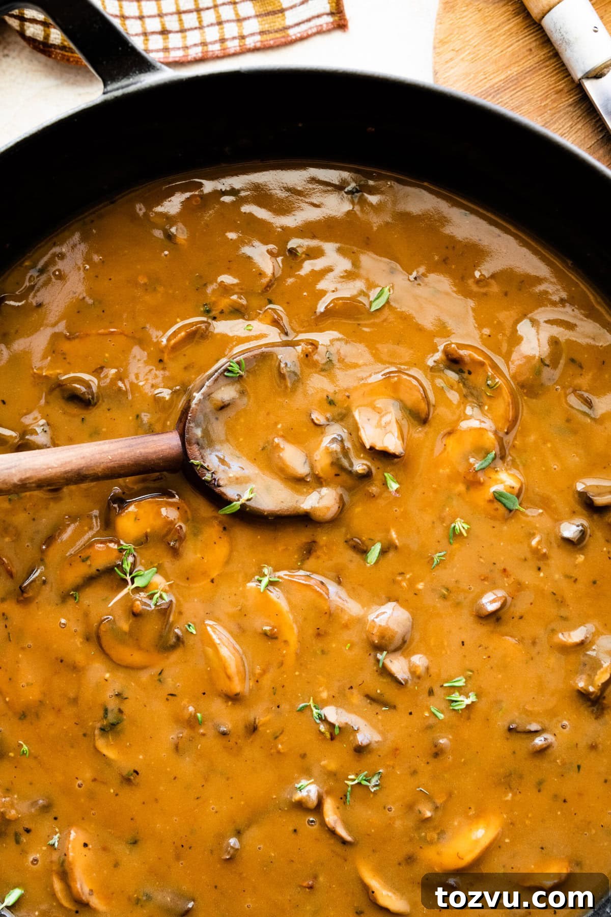 How to Make Mushroom Gravy from Scratch 2 Easy mushroom gravy in a skillet pan with wooden spoon.