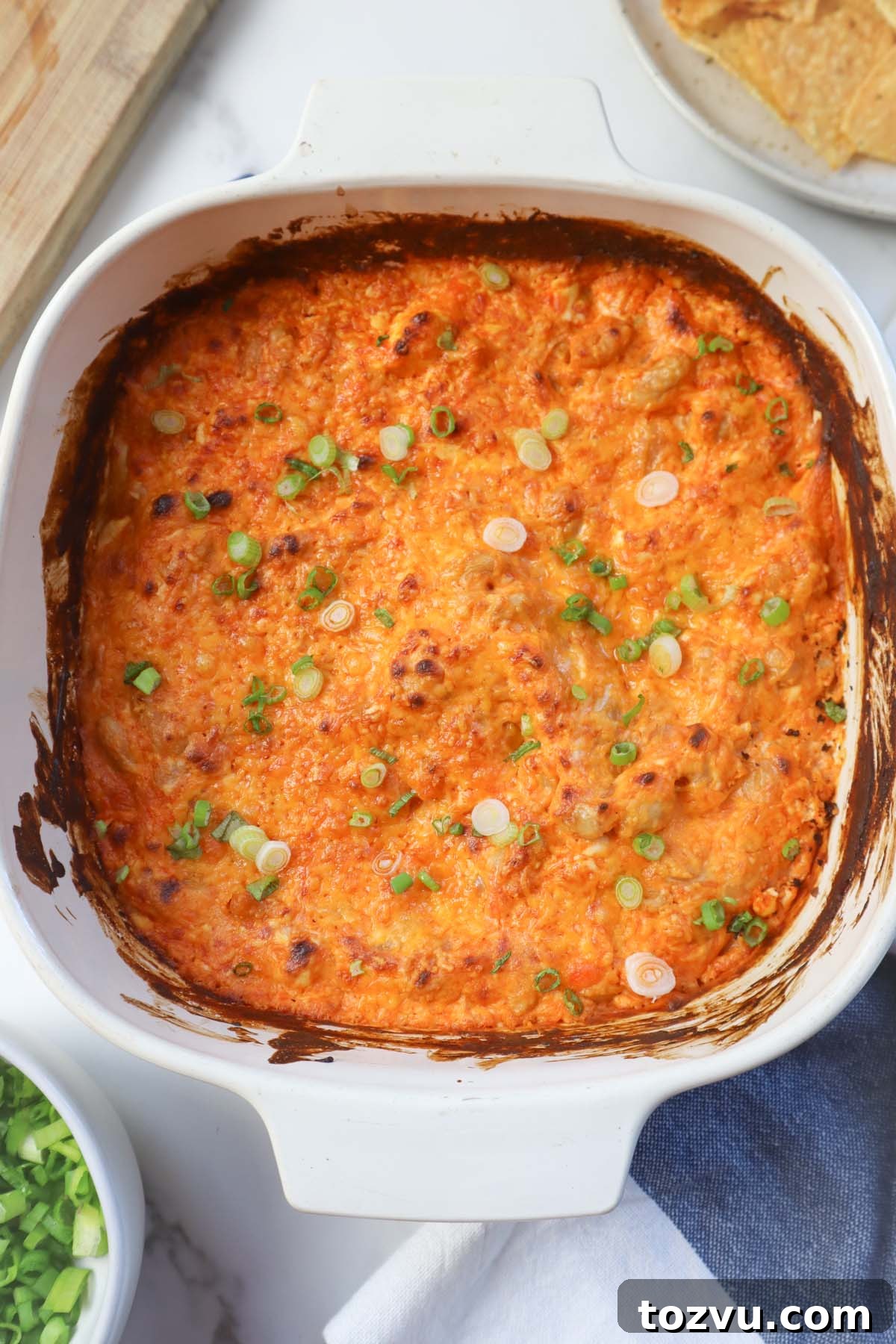 white glass dish with roasted bean dip topped with green onion