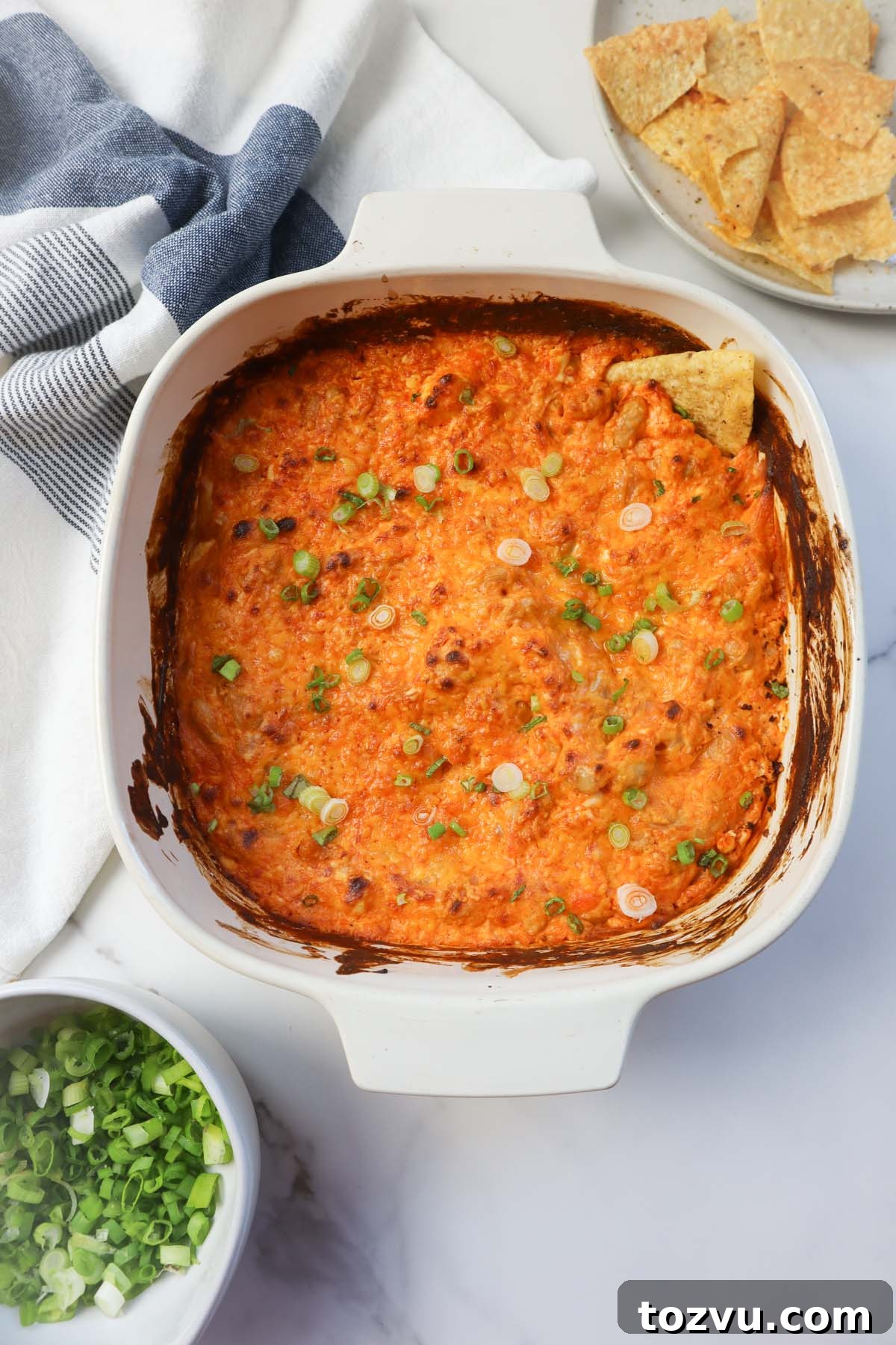 white glass baking dish with buffalo dip topped with green onion