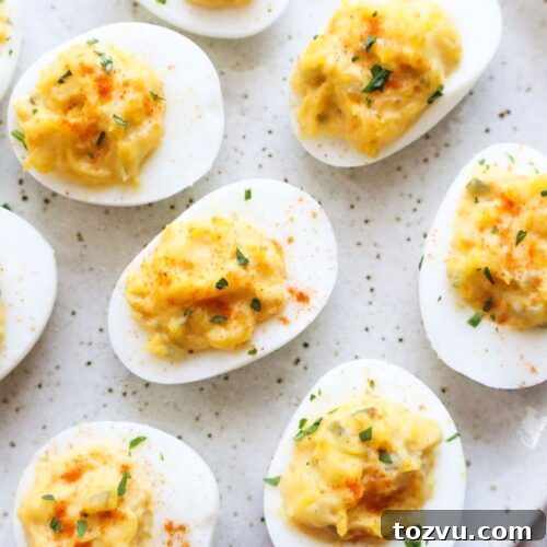 plate with dairy free deviled eggs topped with paprika and minced parsley.