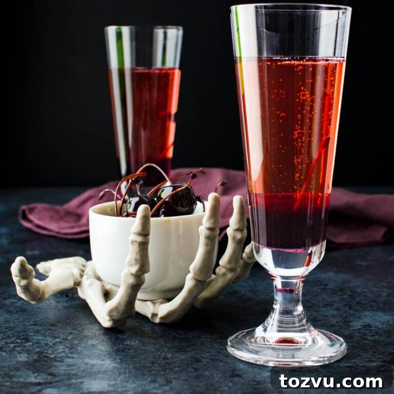 Blood Orange Champagne Bellini 7 A skeletal hand holding a bowl of amarena cherries next to two bloody bellinis.