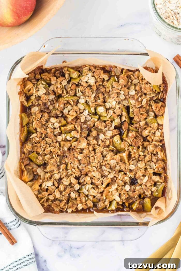 Baked apple crumble bars in a glass baking dish lined with parchment paper.