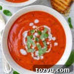 Dairy free tomato soup in a bowl with shredded basil leaves and coconut cream drizzled on top.