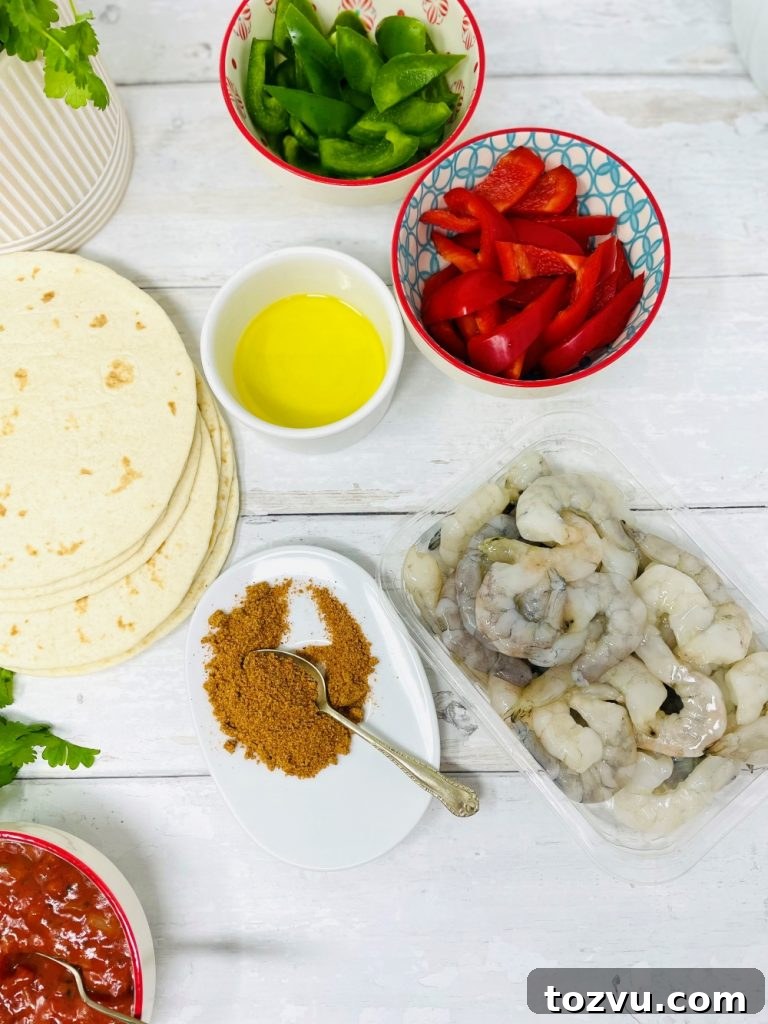 20-Minute Shrimp Fajitas with Peppers and Lime 3 ingredients for king prawn fajitas - diced red and green peppers in bowls, packet of raw king prawns, heaped tablespoon of fajita seasoning all on a white table ready to cook