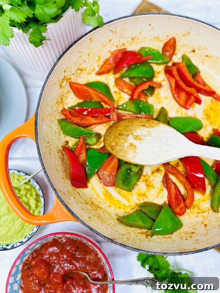 20-Minute Shrimp Fajitas with Peppers and Lime 5 red and green peppers being fried in a skillet pan with fajita seasoning