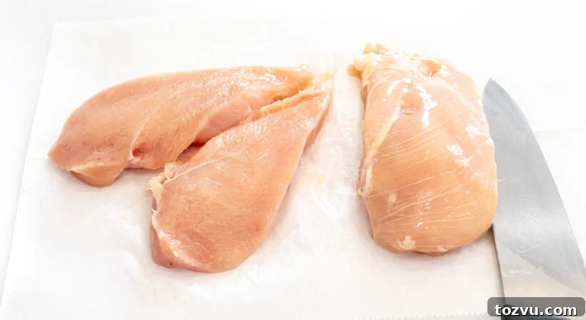 Juicy Air Fryer Chicken Breast Recipe 4 Raw chicken on a cutting board with a chef's knife.