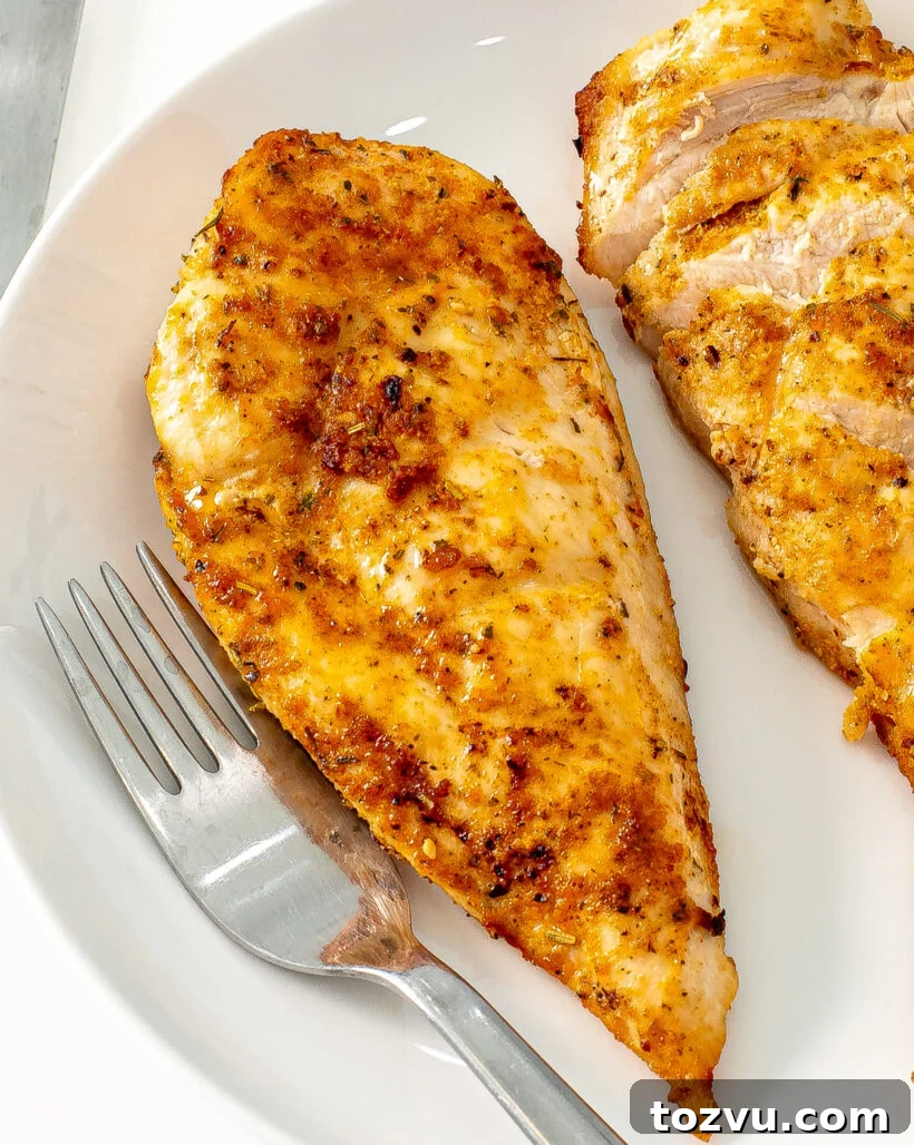 Juicy Air Fryer Chicken Breast Recipe 5 Chicken breast on a plate with some of it sliced off.