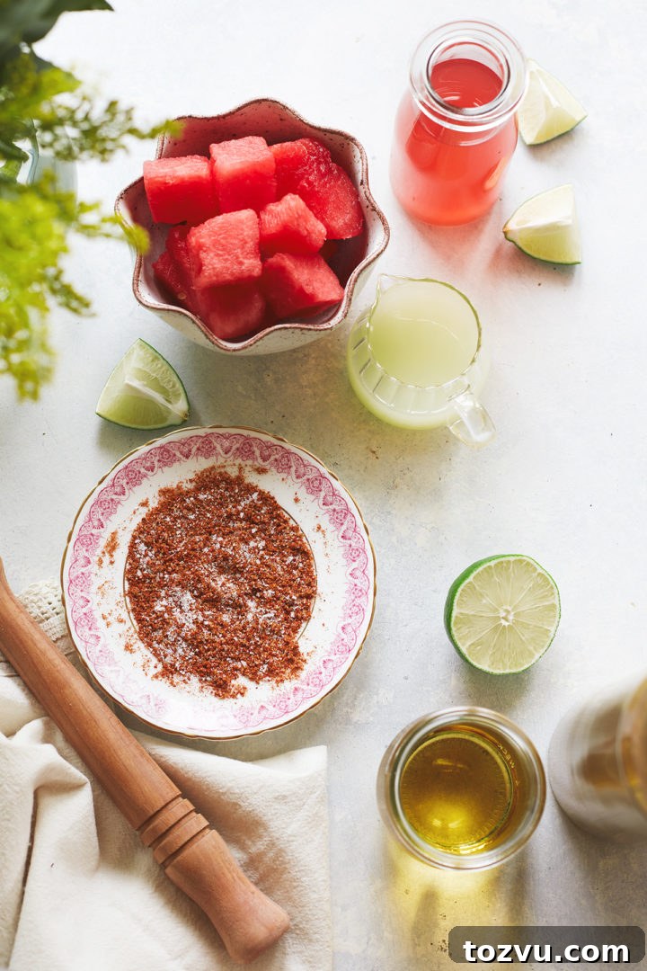 ingredients needed to make fresh watermelon margarita arranged in various dishes on a light surface