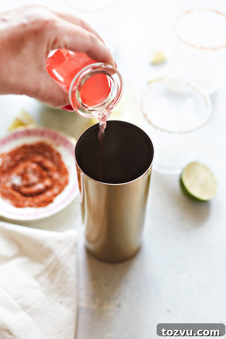 woman adding fresh watermelon juice to a cocktail shaker