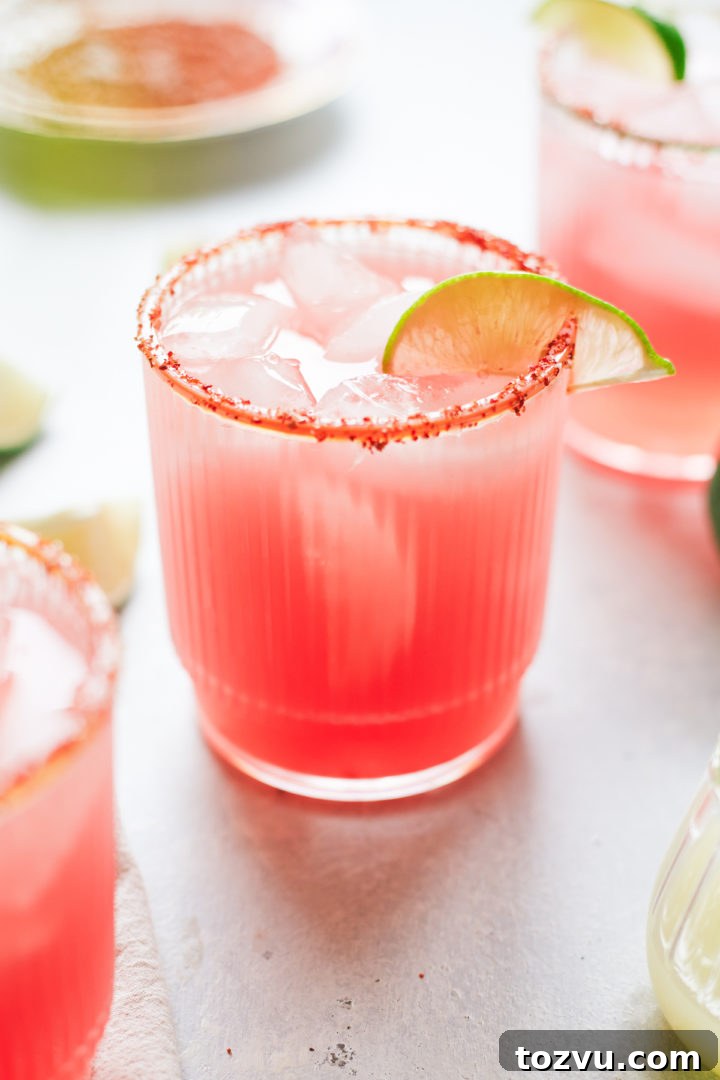 close up of a glass of watermelon margarita with lime garnish