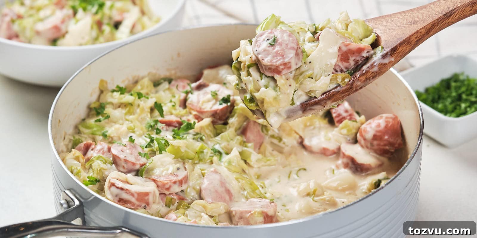 17 Thanksgiving Recipes Ready in Minutes 17 A skillet containing a creamy cabbage and sausage alfredo garnished with herbs.