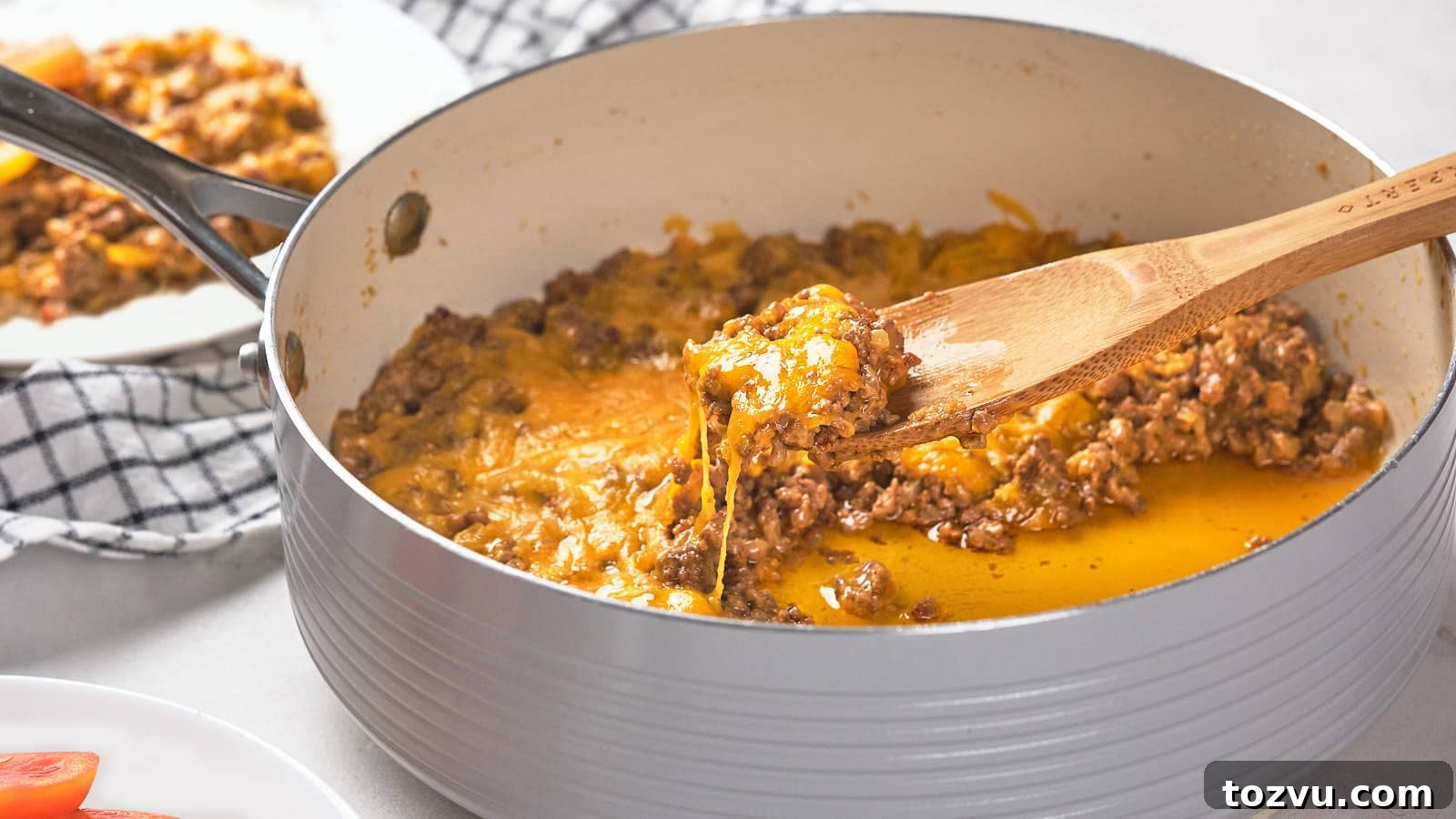 17 Thanksgiving Recipes Ready in Minutes 5 A wooden spoon scoops a portion of cooked ground meat with melted cheese from a pan.