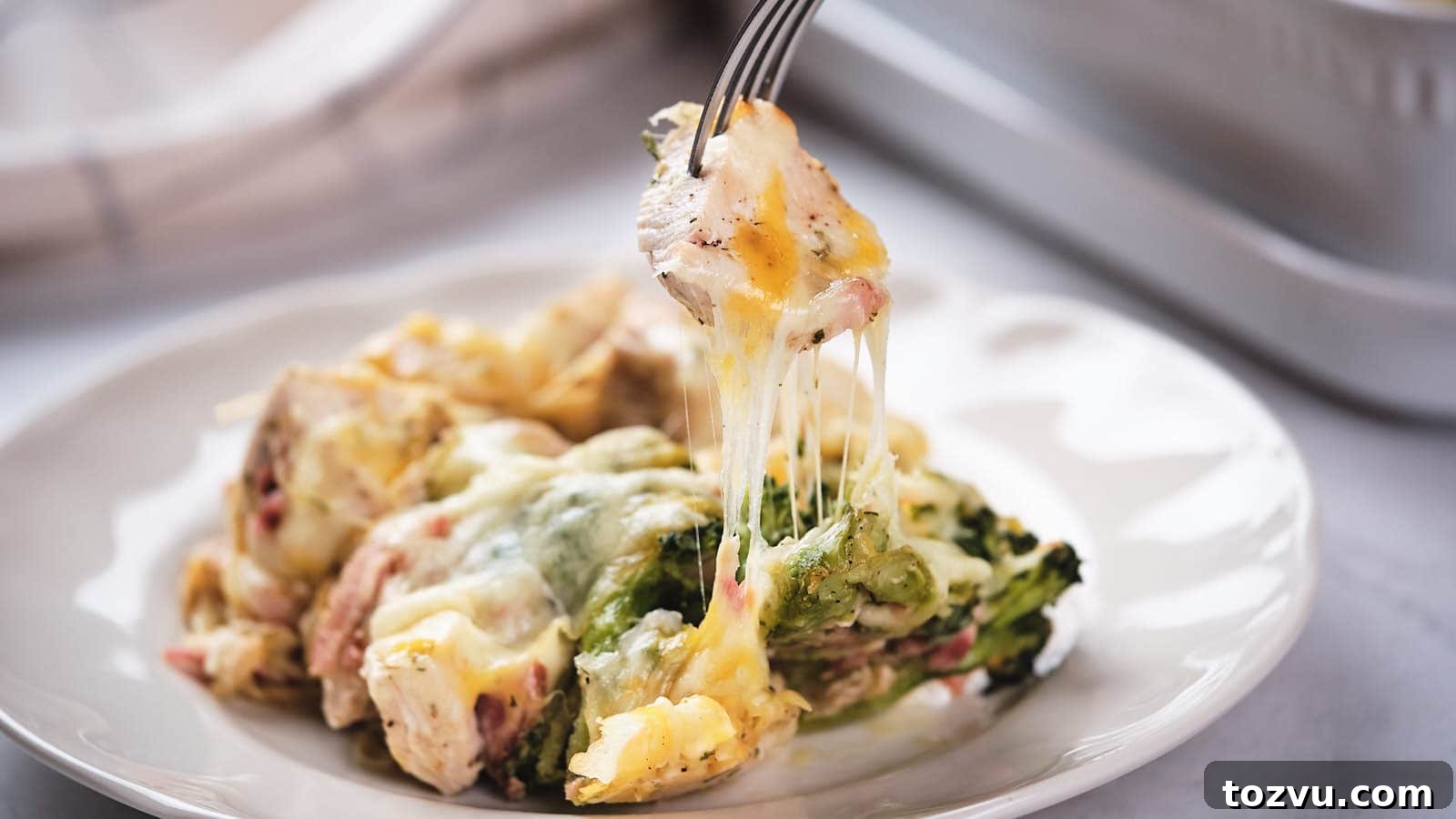17 Thanksgiving Recipes Ready in Minutes 7 A fork lifting a portion of chicken bacon ranch casserole from a white plate.