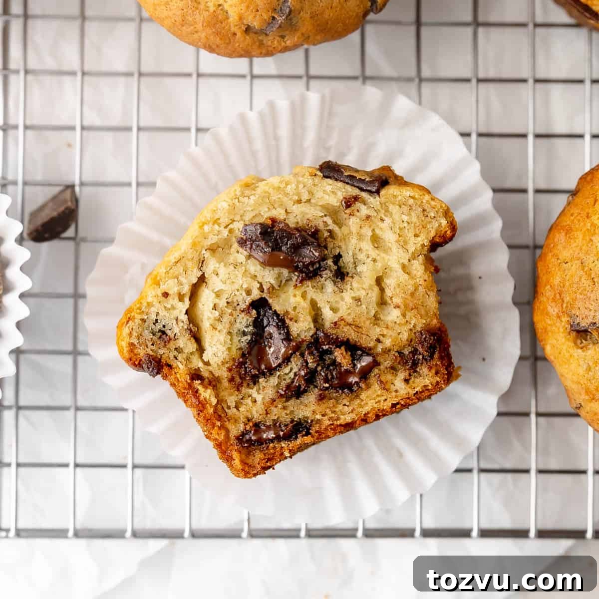 A chocolate chunk banana muffin cut in half on a muffin paper.