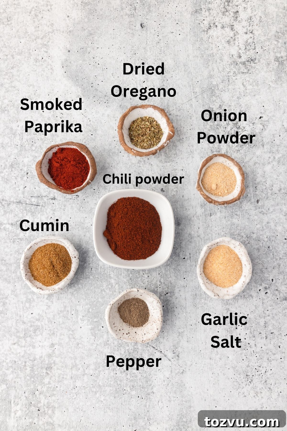 Homemade Chicken Taco Seasoning Mix 3 Ground spices for seasoning, including smoked paprika, dried oregano, onion powder, chili powder, cumin, garlic salt, and pepper in small bowls, flat lay style.