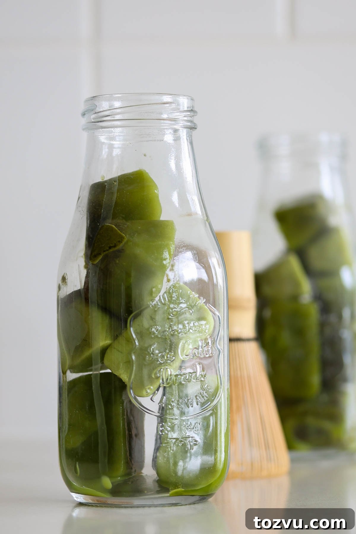 Matcha Ice Cubes for Iced Lattes, Smoothies and Cold Brew 2 Two bottler full of matcha ice cubes, and a bamboo whisk.