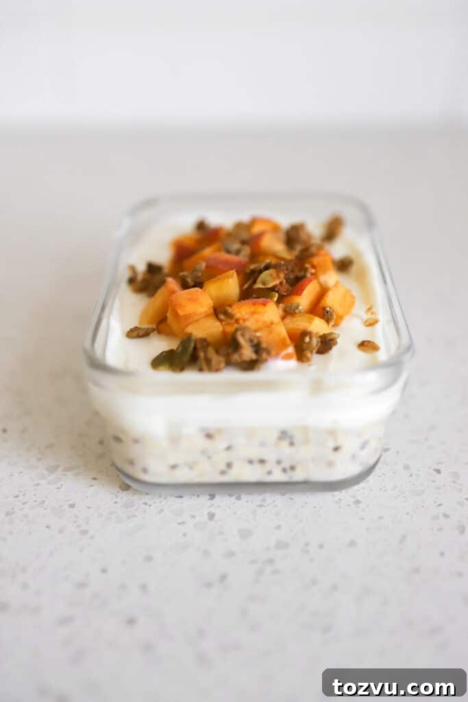 Peaches and Cream Overnight Oats: Creamy No-Cook Breakfast 3 peaches and cream overnight oats with fresh peach slices and granola on top in glass dish on white countertop