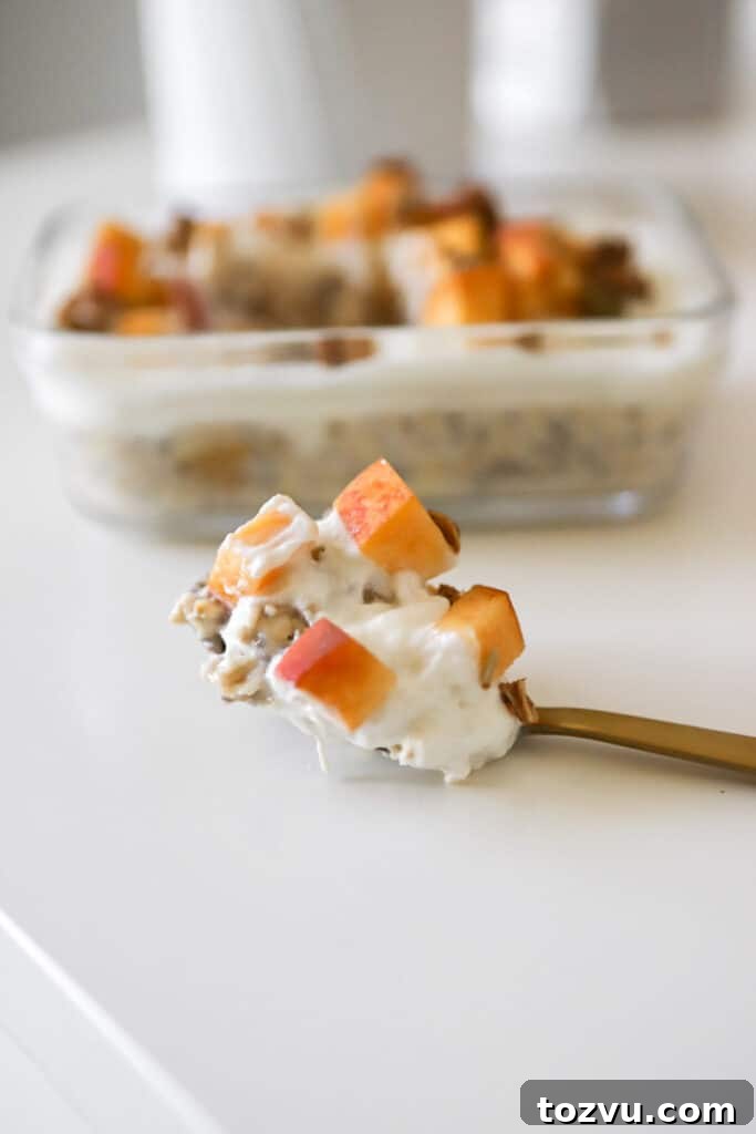Peaches and Cream Overnight Oats: Creamy No-Cook Breakfast 5 a spoon with fresh peaches and cream overnight oats with a casserole dish with oats in the background