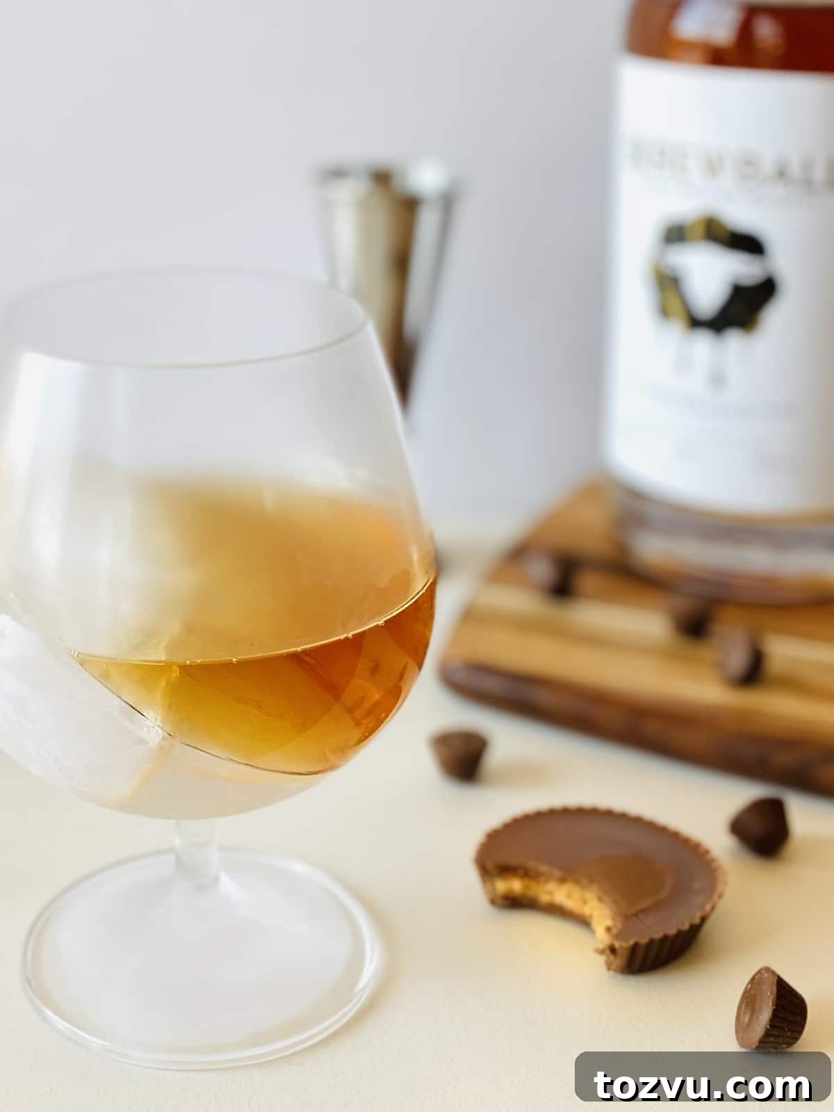 Peanut Butter Whiskey: Brands, Recipes & Cocktail Ideas 2 peanut butter whiskey in a brandy snifter with ice and a peanut butter cup on the side