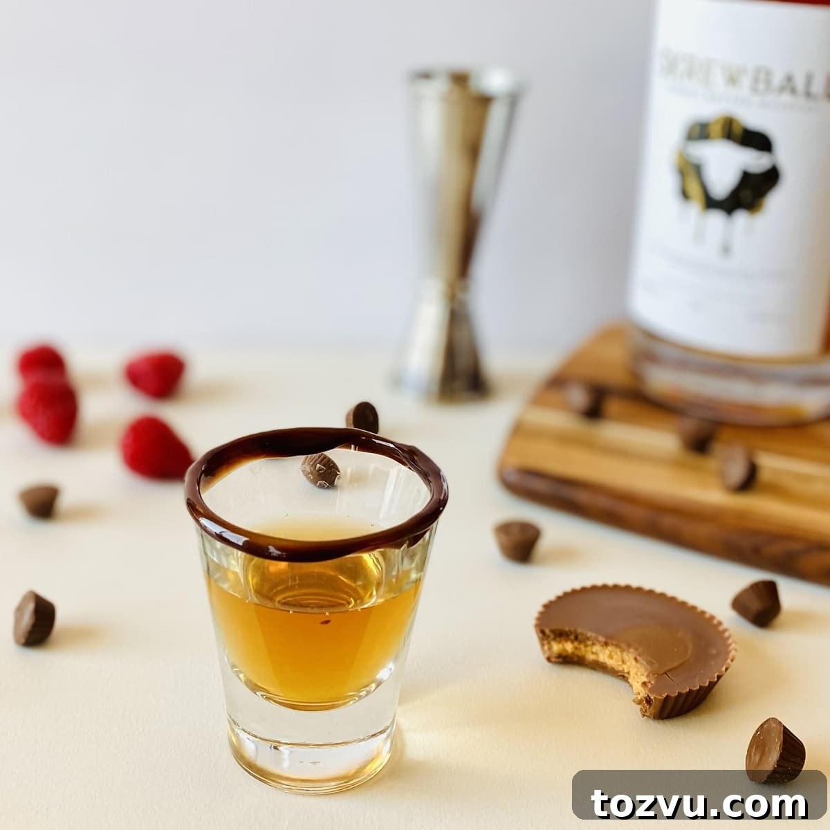Peanut Butter Whiskey: Brands, Recipes & Cocktail Ideas 8 peanut butter whiskey cocktail in a shot glass with a chocolate rim next to a peanut butter cup with a bite out of it